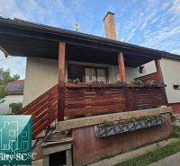Rodinný dům v obci Tureň s dřevěným zábradlím a květinovou výzdobou na verandě.