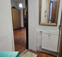 Interiér rodinného domu s podlahou s dřevěným dekorem, zrcadlem a radiátorem.