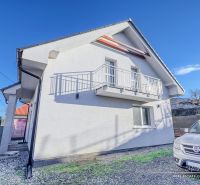 Rodinný dům v Hrnčiarovcích nad Parnou s bílou fasádou a balkonem na kamínkovém dvoře.