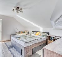 Světlá podkrovní ložnice s pohodlnou postelí a výhledem, rodinný dům.