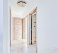 Chodba v rodinném domě s dlažbou, dřevěnými dveřmi a stylovým osvětlením.