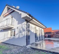 Rodinný dům v Hrnčiarovcích nad Parnou s betonovou terasou a balkonem v patře.