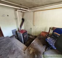 Stará kotelna v rodinném domě s kancelářskými židlemi a potrubím na stěně.