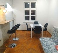 Jídelní kout s bílým stolem, šedými židlemi a podlahou s dřevěným dekorem v 2-pokojovém bytě.