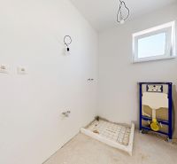 Nedokončená koupelna v rodinném domě s přípravou na instalace a oknem na stěně.