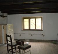 Interiér rodinného domu s podlahou s dřevěným dekorem a židlí pod oknem.