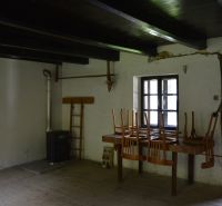 Interiér rodinného domu s sporákem, stolem, židlemi a podlahou s dřevěným dekorem.