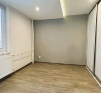 Prázdný pokoj se skříní a podlahou s dřevěným dekorem ve 4pokojovém bytě.