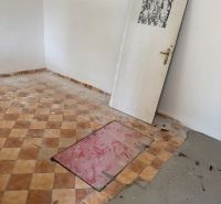 Pokoj v chatě s kachlovou podlahou a dveřmi bez pantů.