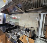 Kuchyňské zařízení v gastro prostorech s grilem a fritézou na přípravu jídel.