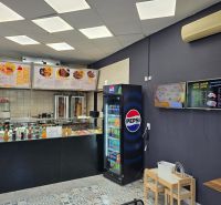 Gastro prostory s prodejem nápojů a jídel, podlaha s dřevěným dekorem, menu na stěnách.