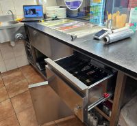 Kuchyňská linka v gastro prostorech s nerezovým vybavením a pokladnou.
