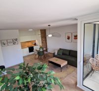Interiér 2-pokojového bytu s podlahou s dřevěným dekorem, moderním nábytkem a balkonem.