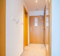 Chodba rekreačního apartmánu s dřevěnými prvky a kobercem.