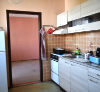 Kuchyně ve 3-pokojovém bytě s dlaždicovým obkladem a podlahou s dřevěným dekorem.