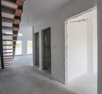 Interiér 4-pokojového bytu se schodištěm a velkými okny, neutrální barvy stěn.