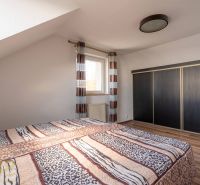 Ložnice ve 4pokojovém bytě s postelí, velkou skříní a podlahou s dřevěným dekorem.