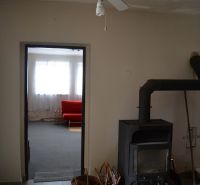 V rodinném domě je stropní ventilátor, kamna a červená pohovka v pozadí.