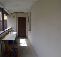 Chodba s bílými stěnami, praskliny na podlaze, stůl, dveře v rodinném domě.