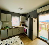 Kuchyně rekreačního apartmánu s podlahou s dřevěným dekorem a světlým nábytkem.