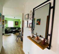Chodba v rekreačním apartmánu s podlahou s dřevěným dekorem a zrcadlem na stěně.