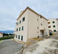Rekreační apartmán na Brači se vstupem vedoucím z betonové příjezdové cesty.