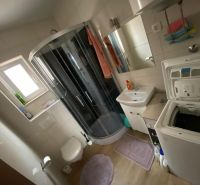 Koupelna v rekreačním apartmánu s pračkou, sprchovým koutem a umyvadlem.