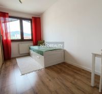 Světlý pokoj s postelí, stolem a podlahou s dřevěným dekorem ve 3-pokojovém bytě.