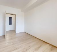 Pokoj s bílými stěnami a podlahou s dřevěným dekorem v 2-pokojovém bytě.