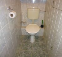 Koupelna s toaletou v 2-pokojovém bytě s kachličkovým obkladem a podlahou.