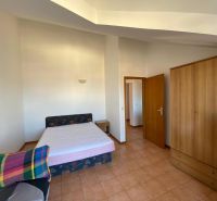 Ložnice v rekreačním apartmánu s postelí, skříní a televizorem.