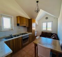 Kuchyně s dřevěným dekorem, jídelním stolem a pohovkou v rekreačním apartmánu.