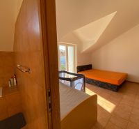Interiér rekreačního apartmánu s pohovkou, postelí a dětskou postýlkou.