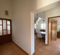 Chodba v rekreačním apartmánu s keramickou podlahou, jídelní kout a pokoj v pozadí.