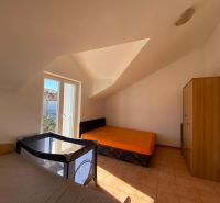 Ložnice v rekreačním apartmánu s postelemi, skříní a dětskou postýlkou.