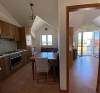 Kuchyně rekreačního apartmánu s dřevěnými skříňkami a výhledem na moře.
