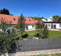 Rodinný dům ve městě Berg se zahradou, plotem a červenou střechou.