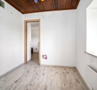 Bílá místnost s dřevěným stropem a podlahou s dřevěným dekorem v rodinném domě.