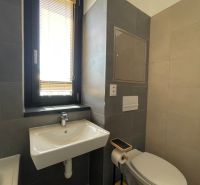 Koupelna s umyvadlem, WC a oknem ve 2-pokojovém bytě.