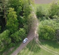 Auto na lesní cestě mezi zelenou vegetací v Rekreačních pozemcích ve Streženicích.