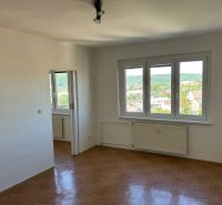 Světlý pokoj se třemi okny a podlahou s dřevěným dekorem v 2pokojovém bytě.