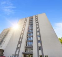 Výškový bytový dům v Bratislavě - Starém Městě s modrou oblohou a parkovištěm.