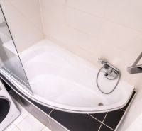 Koupelna s vanou, sprchovou zástěnou a pračkou ve 3-pokojovém bytě.