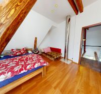 Podkrovní pokoj v rodinném domě s postelí, dekorativním dřevem a podlahou s dřevěným dekorem.