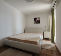 Světlá ložnice v rodinném domě s postelí a podlahou s dřevěným dekorem.