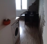 Jídelní kout s podlahou s dřevěným dekorem, pračkou a zajímavou stěnou ve 2-pokojovém bytě.