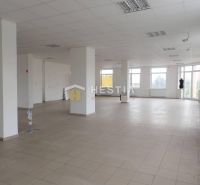 Prostorné obchodní prostory s velkými okny a podlahou z dlažby poskytují světlé prostředí.