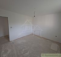 Pokoj v rodinném domě s bílými stěnami a podlahou s dřevěným dekorem.