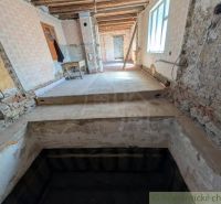 Interiér rodinného domu v rekonstrukci s odkrytými zdmi a schodištěm.