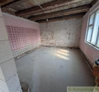 Interiér s odhalenými cihlovými stěnami a dřevěnými stropními trámy v rodinném domě.